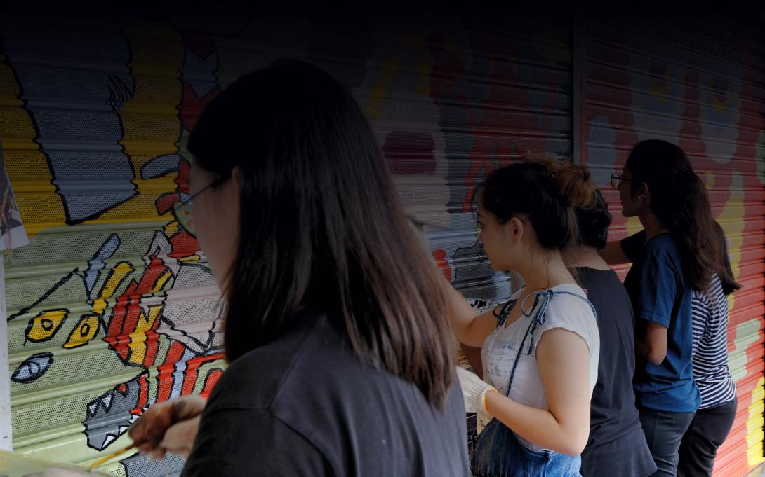 Photo of young women painting artwork on steel doors