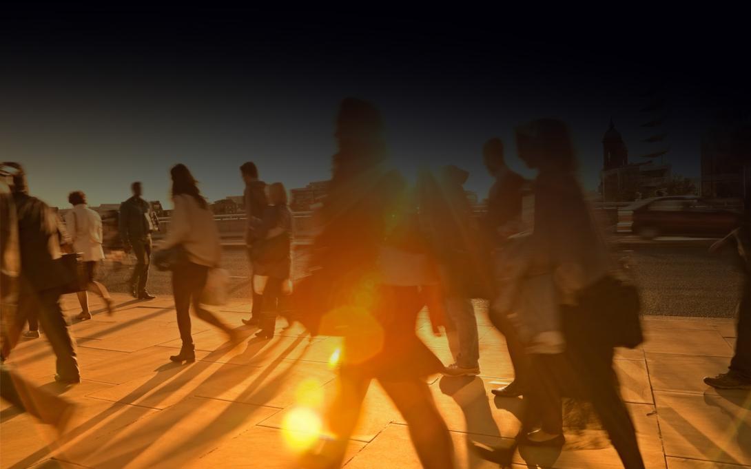 Photo of people walking on pavement with intense sunshine in the background