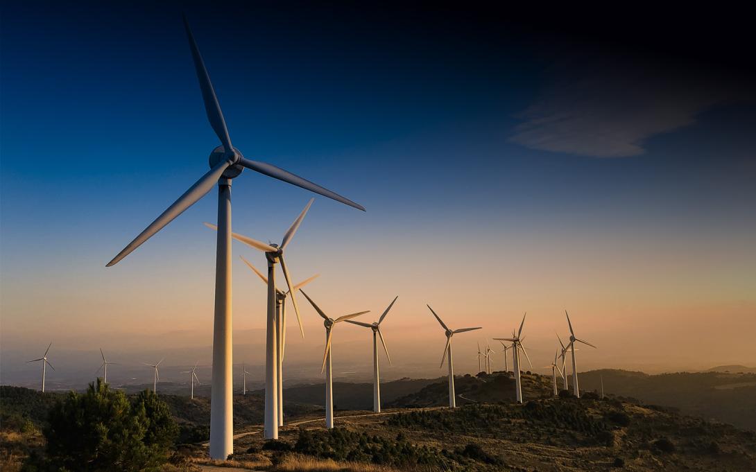 Photo of wind turbines in field with blue sky